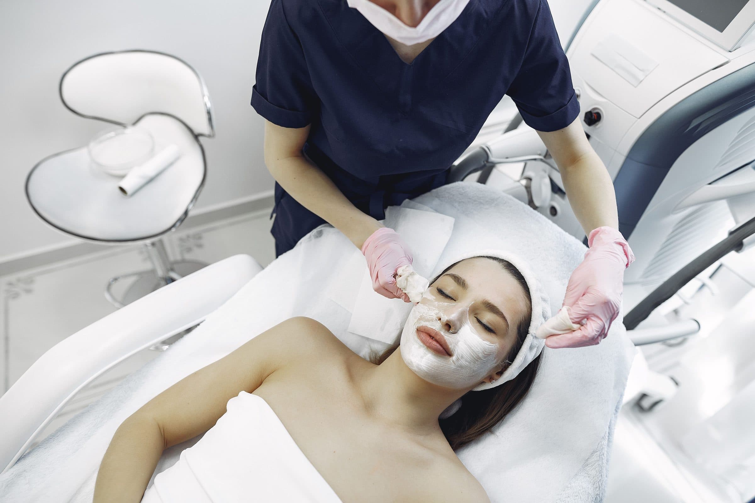 Client relaxing during a facial treatment, wrapped in a soft towel